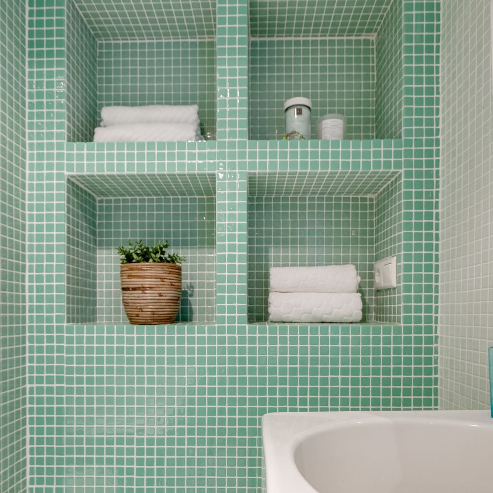 Nichos revestidos em pastilha verde com toalhas e uma planta